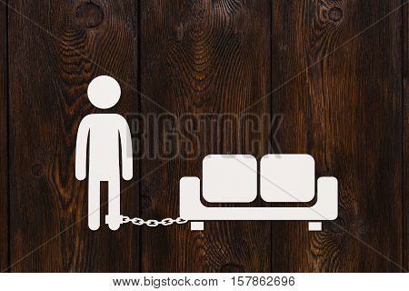 Paper man chained to sofa, laziness or laisure concept, abstract conceptual image