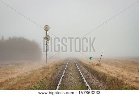 A pair of rails recede into the distant prairie fog