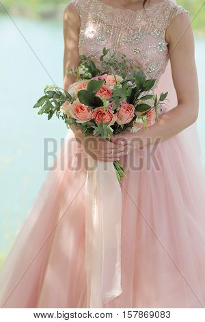 Beautiful bridal bouquet in hands of the bride. Wedding bouquet of peach roses  single-head pink rose aqua eucalyptus ruscus gypsophila