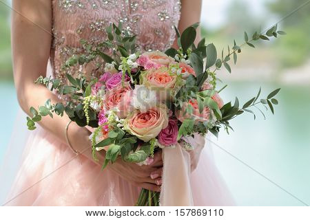 Beautiful bridal bouquet in hands of the bride. Wedding bouquet of peach roses  single-head pink rose aqua eucalyptus ruscus gypsophila