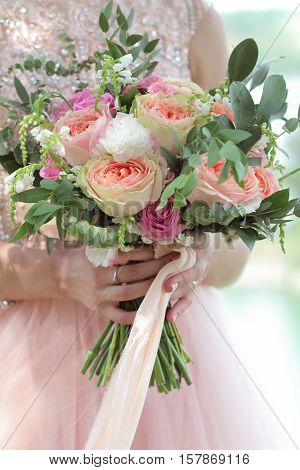 Beautiful bridal bouquet in hands of the bride. Wedding bouquet of peach roses  single-head pink rose aqua eucalyptus ruscus gypsophila