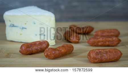 Several small Salimis on a wooden tray with a corner cheese