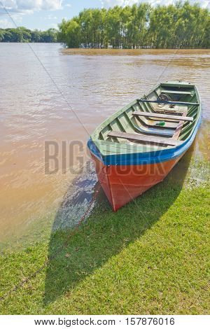 A wood boat stopped on grass with Rio Pardo river in background