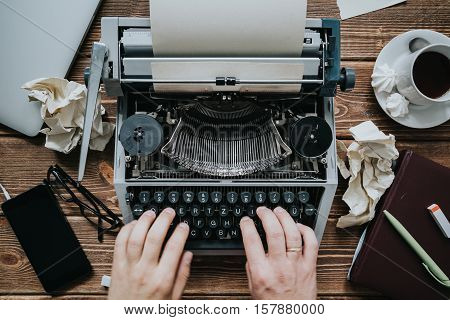 Writer typing with retro writing machine. View from above.