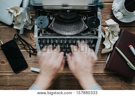 Writer typing with retro writing machine. View from above.