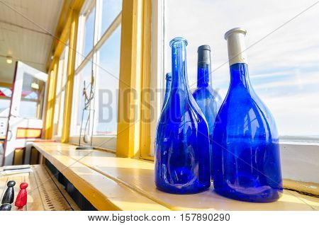 Blue bottles in a window beside the sea, Newfoundland Canada.
Wide Angle view, Blue glass bottles decorate a shelf at a window with a view to the Atlantic in Grand Bank Newfoundland.