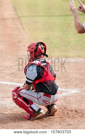 American baseball catcher in a black and grey uniform behind home plate.