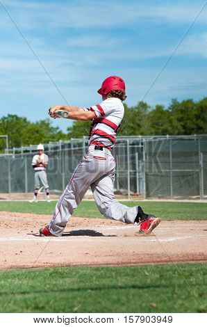 Teen baseball player swinging a baseball bat.