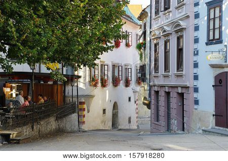 Gmina Škofja Loka, Škofja Loka, Slovenia - September 25 2016: old town, Mestni trg (City Square). Typical buildings, windows decorated with flowers. Some people are visible in the garden pub.