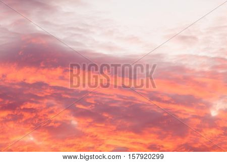Romantic and dramatic cloud formation on dusk sky. Red and black warm landscape with sunlight.