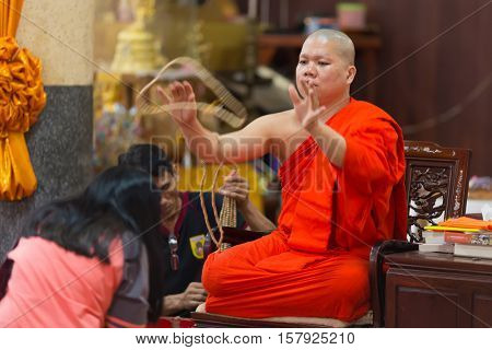 SANGKHLABURI, THAILAND, JANUARY 24, 2016 : A skilled Buddhist monk is blessing a woman by throwing a rosary necklace around his neck in the Wat Wang Wiwekaram temple, Sanghklaburi, Thailand