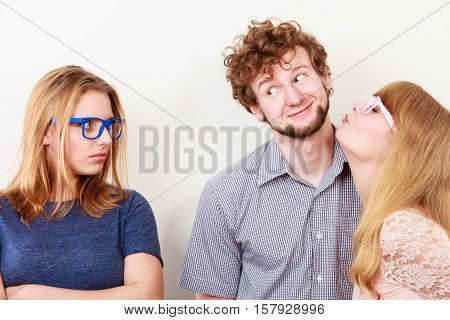Jealousy and betrayal concept. Abandoned jelous girl watching on happy couple - young attractive blondie woman kissing handsome boy.