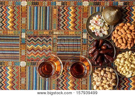 sweets, dates and tea on a traditional Arabian carpet