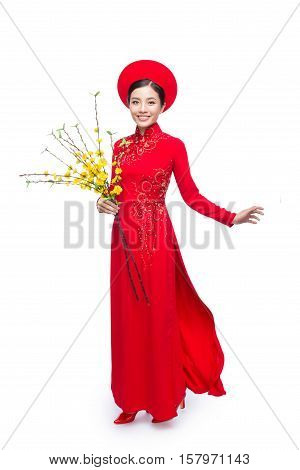 Portrait of a beautiful Asian woman on traditional festival costume Ao Dai holding Hoa Mai tree (Ochna Integerrima) flower. Tet holiday. Lunar New Year.