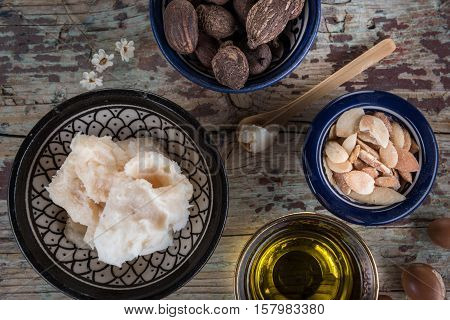 Shea butter and nuts and argan fruits and oil on a wooden table