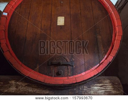 Picture of a brown wine barrel stacked in the old cellar of the winery. Background of the wooden barrel made of brown planking.