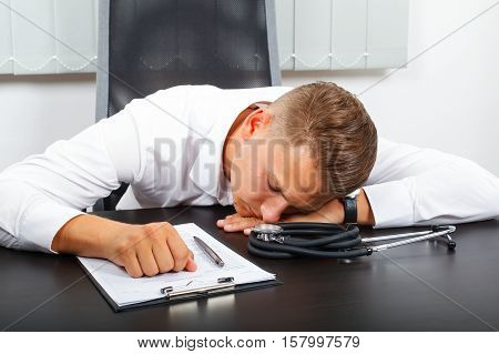 Photo of a tired young male doctor in his medical office