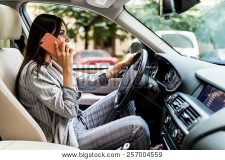 Portrait Of Woman Driver Talking Her Mobile Phone While Driving Car.