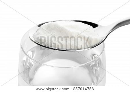 Spoon With Baking Soda Over Glass Of Water On White Background