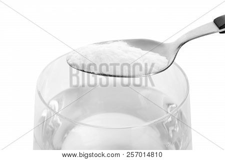 Spoon With Baking Soda Over Glass Of Water On White Background