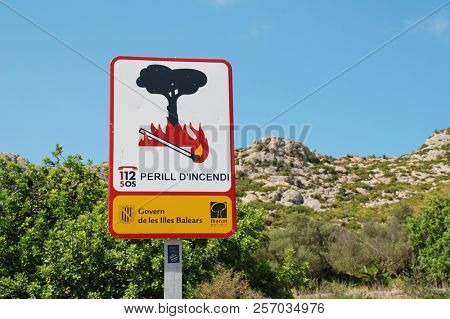 MAJORCA, SPAIN - SEPTEMBER 5, 2017: A Government sign warning of the risk of fire by the Tramuntana mountains at Puerto Pollensa. The sign marks the start of the Boquer valley walking trail.