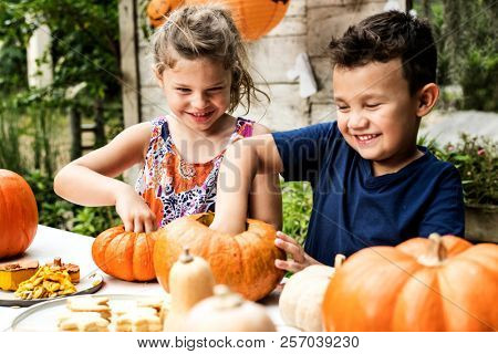 Young kids carving Halloween jack-o-lanterns