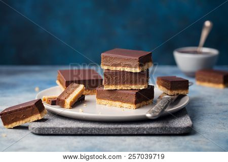 Chocolate Caramel Slices, Bars, Millionaires Shortbread On A Grey Plate. Blue Background
