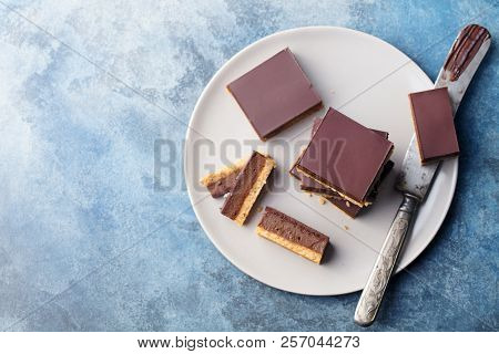 Chocolate Caramel Slices, Bars, Millionaires Shortbread On A Grey Plate. Blue Background. Top View