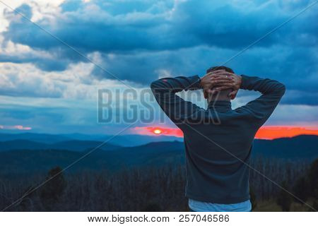 Travel, freedom and tourism concept - man standing on top of cliff in summer beauty evening in Altai mountains