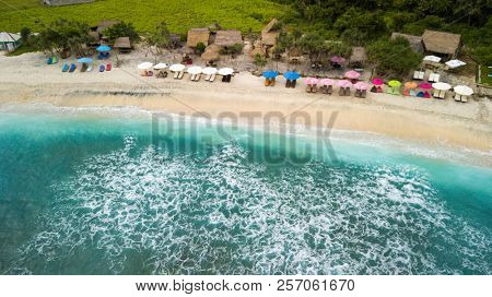 Aerial shot of the Atuh beach bay with sunshade and wooden bars in the Nusa Penida island, Bali, Indonesia