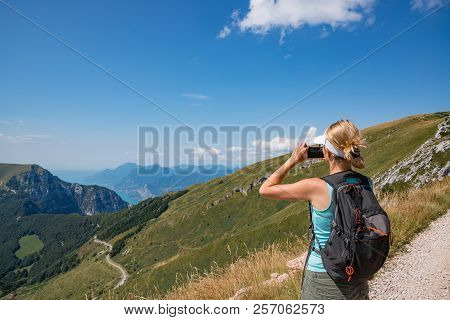 Woman Taking Photo With Her Phone Of Monte Baldo, Road To Monte Altissimo In Italian Alps