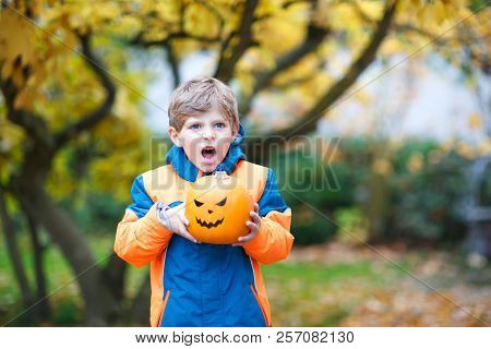 Happy Cute Little Kid Boy With Halloween Pumpkin Lantern. Funny Child In Colorful Clothes Having Fun