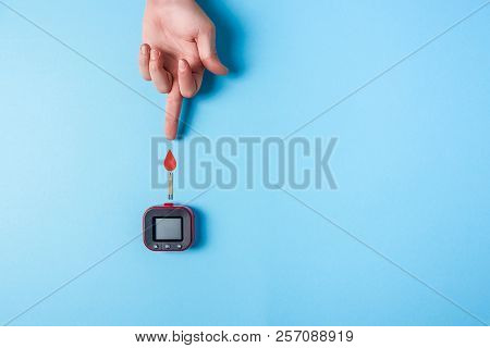 Blood Test. Man's Hand With Red Blood Drop With Blood Glucose Test Strip And Glucose Meter