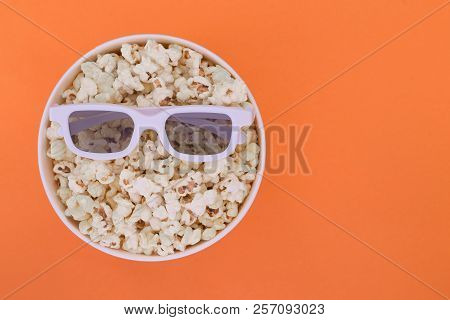 3d Glasses Lie On A Cup With Popcorn Isolated On A Orange Background. Cinema Concept. Flat Lay. Copy