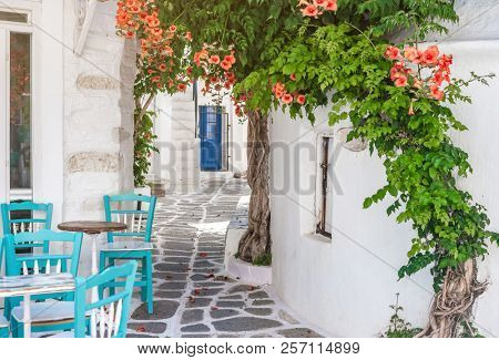 Beautiful narrow street with white houses in Mikonas island, Greece. Traditional narrow street with white facedes of buildings and blue doors