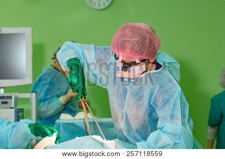 Cosmetic Liposuction Surgery In Actual Operating Room, Group Of Surgeons Working With Cannula