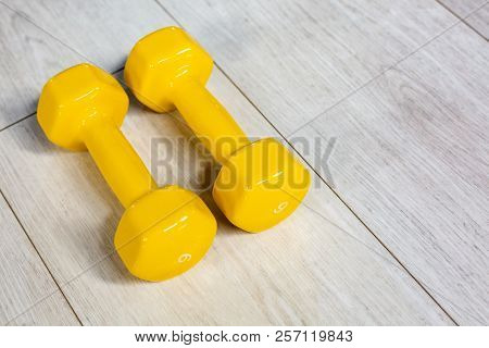 Yellow Modern Dumbbells On A Wooden Floor