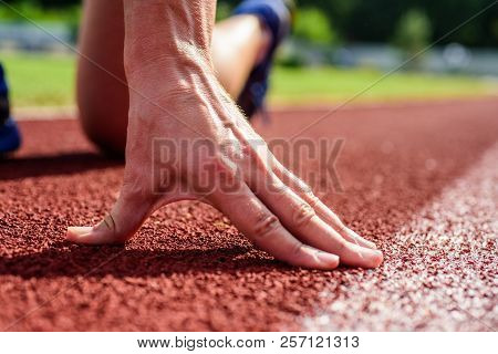 Hand Of Sportsman On Running Track Low Start Position. Runner Ready To Go Close Up. Flexibility Is A