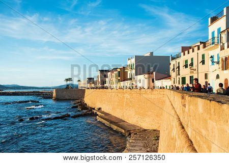 ALGHERO, ITALY - SEPTEMBER 17, 2017: People at the surrounding wall, next to the sea, of the Centro Storico, the old town of Alghero, in Sardinia, Italy