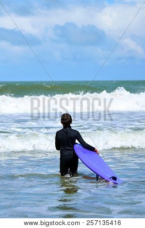 Little Boy Going To The Sea Waves With A Surfboard In His Hands. Surfer School. Kids Outdoor Water S