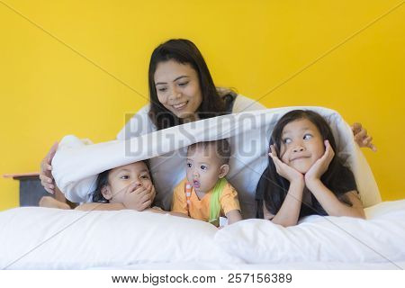 Babysitting Playing With Three Playful Kids Carrying On The Bed; Widow Young Woman And Child Are Enj