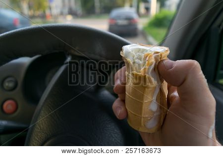 The Driver Holds The Ice Cream While Driving A Car