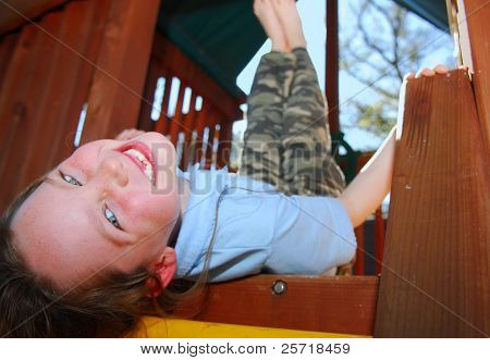 Cute freckle faced girl relaxing and smiling in outdoor treehouse
