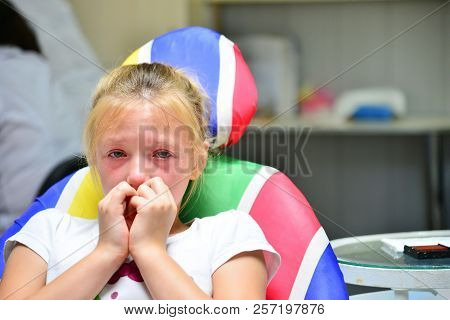 A Little Girl At The Dentist Is Crying With Tears At A Doctor's Appointment While Treating A Tooth.