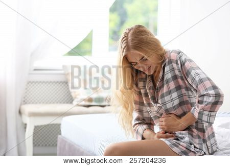 Young Woman Suffering From Pain In Bedroom. Gynecology Concept