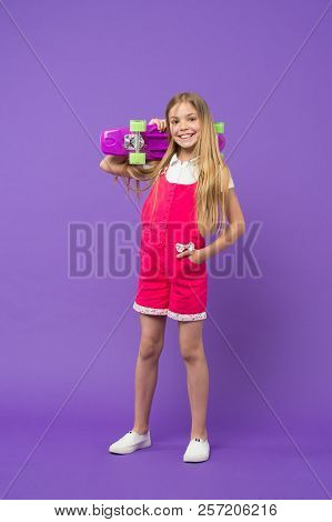 Child With Charming Smile Isolated On Violet Background. Girl With Blond Hair In Pink Jumpsuit And W