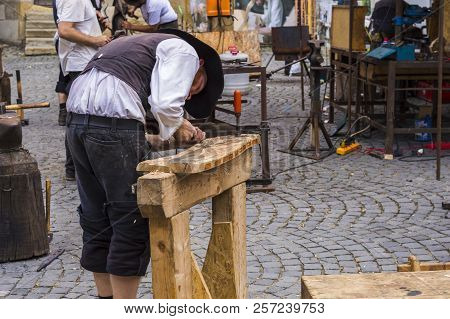 Sibiu, Romania - July 30, 2018: Craftsman In Traditional Medieval Clothing Carwing Wood At Outdoor W