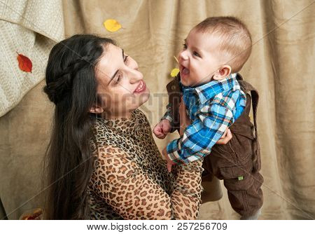 autumn concept - mother and child boy are on yellow leaves with fruits and vegatbles, red apples and pumpkins