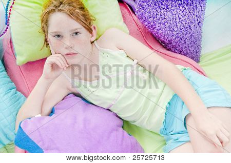 Tweenage girl relaxing on colorful cushions