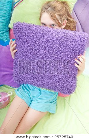 Teenager hiding behind pillow